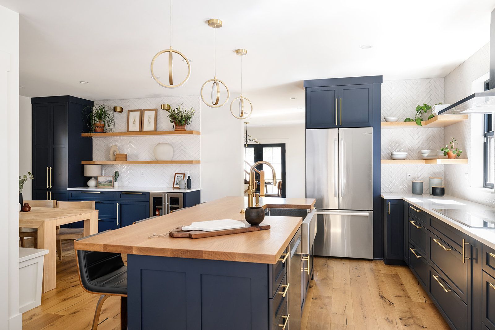 A kitchen with blue cabinets , stainless steel appliances , wooden floors and a large island.