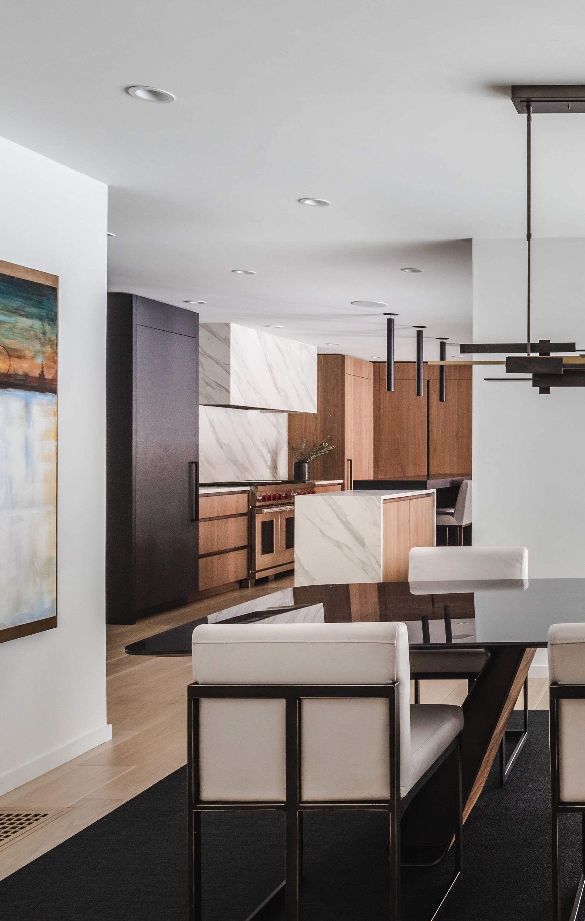 A dining room with a table and chairs and a painting on the wall
