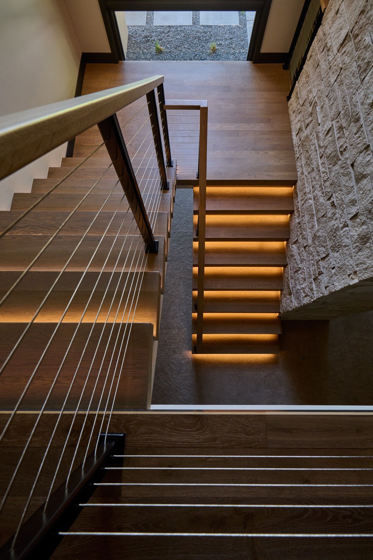 A wooden staircase with a metal railing and lights on the steps.