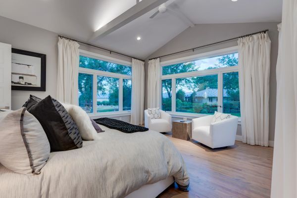 A bedroom with a large bed , chairs and windows