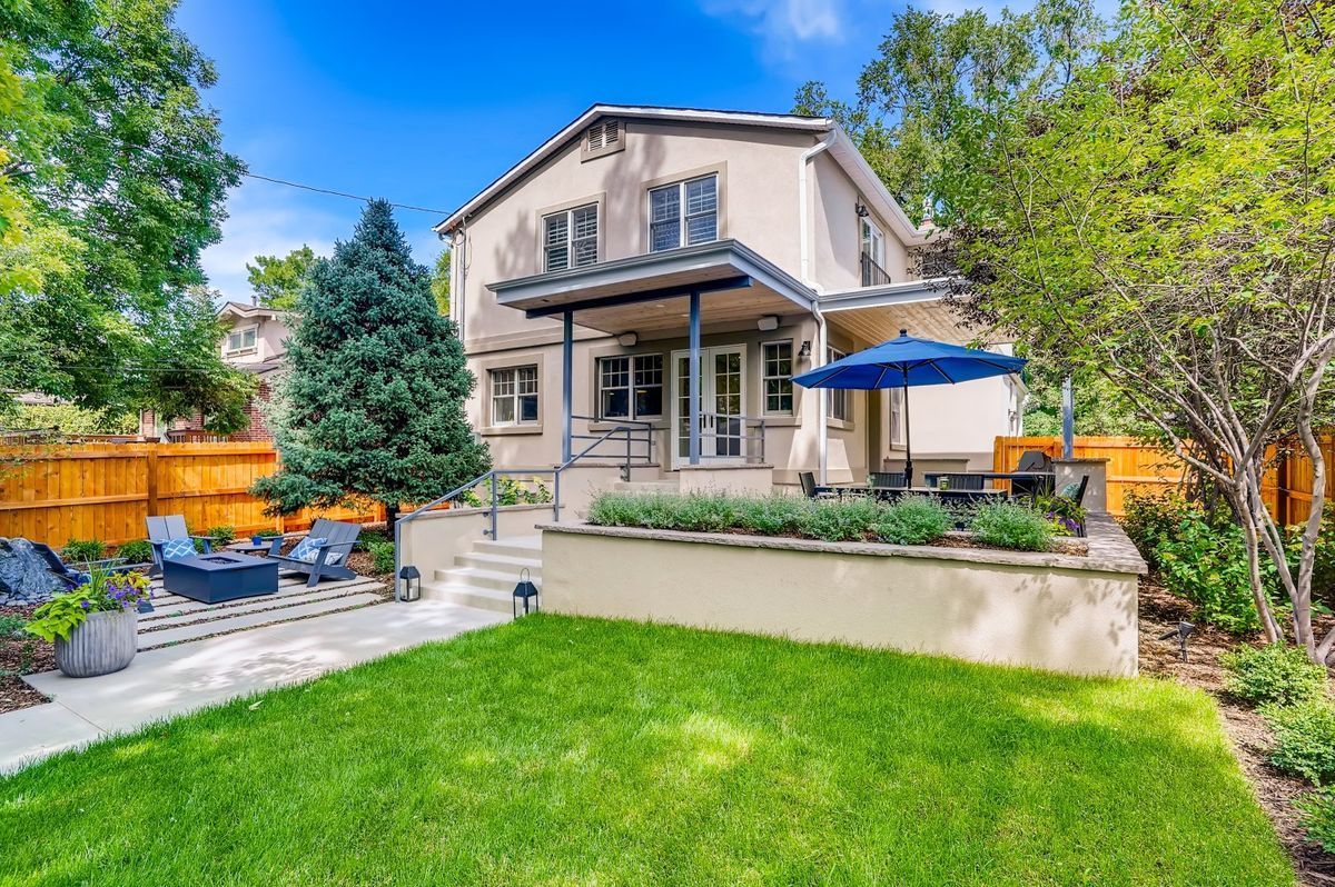 The backyard of a house with a large lawn and patio area.