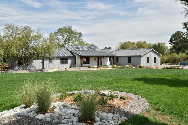 A large house is sitting on top of a lush green field.