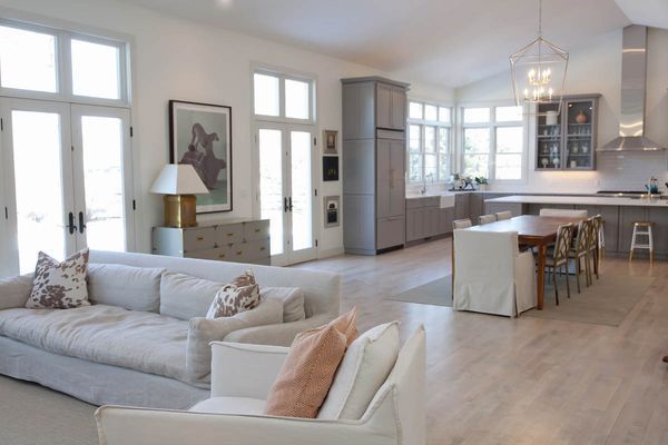 A living room with a couch and chairs and a kitchen.
