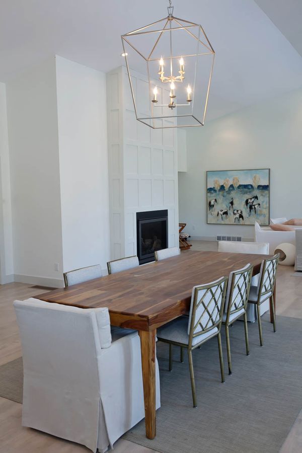 A dining room with a long wooden table and white chairs