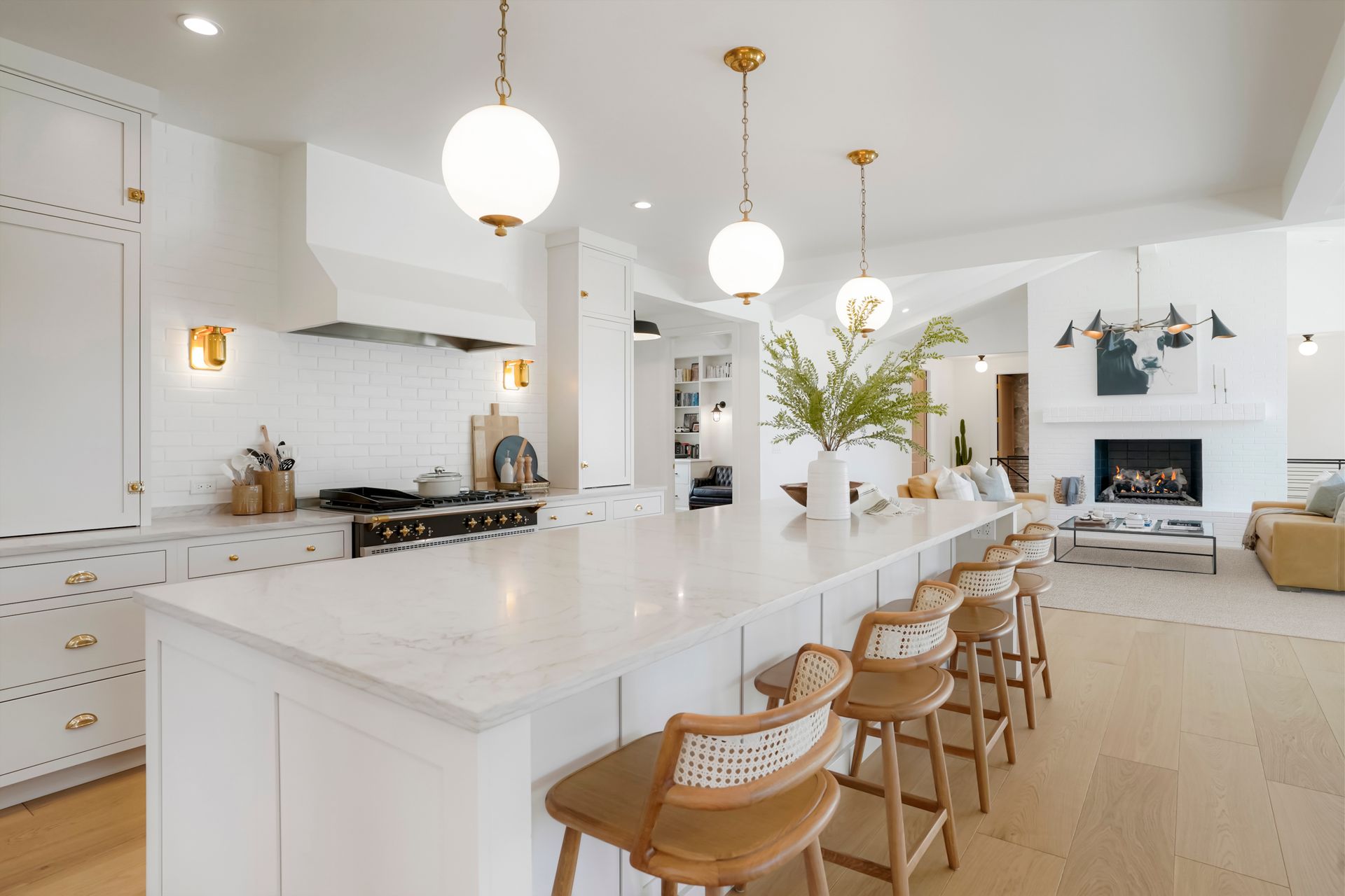 A kitchen with white cabinets and a long island with stools.