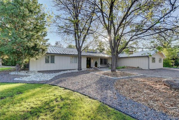 A white house with a metal roof and trees in front of it.