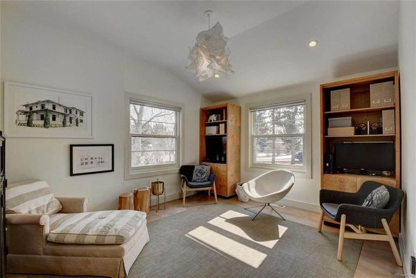 A living room with a couch, chairs, shelves, and a television.