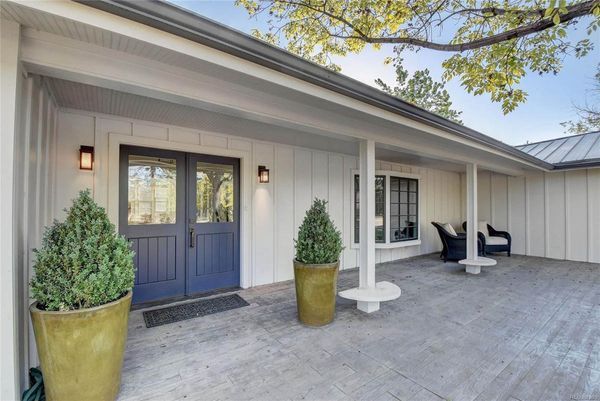 A white house with blue doors and potted plants in front of it.