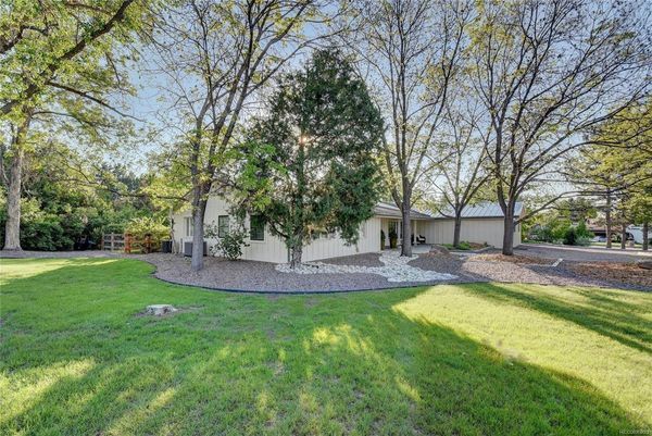 A house with a large lawn and trees in front of it.