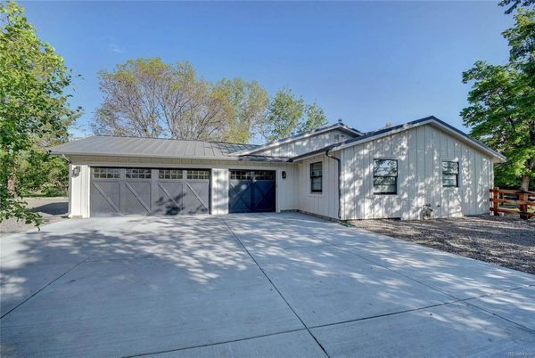 A white house with a garage and a driveway in front of it.