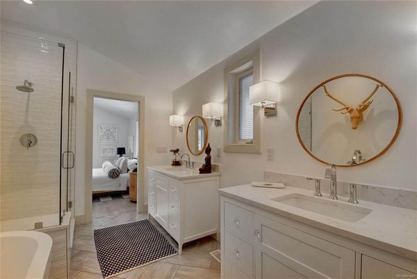 A bathroom with two sinks, a tub, and a deer head on the wall.