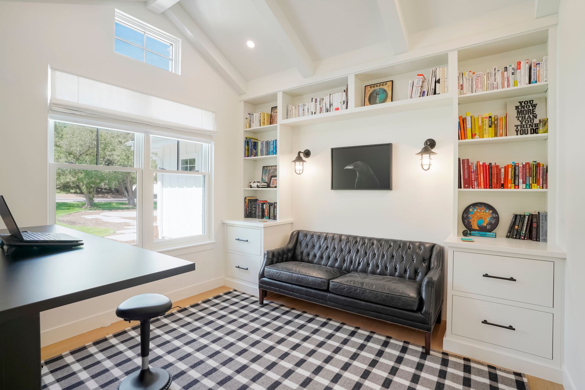 A home office with a couch , desk , and bookshelf.