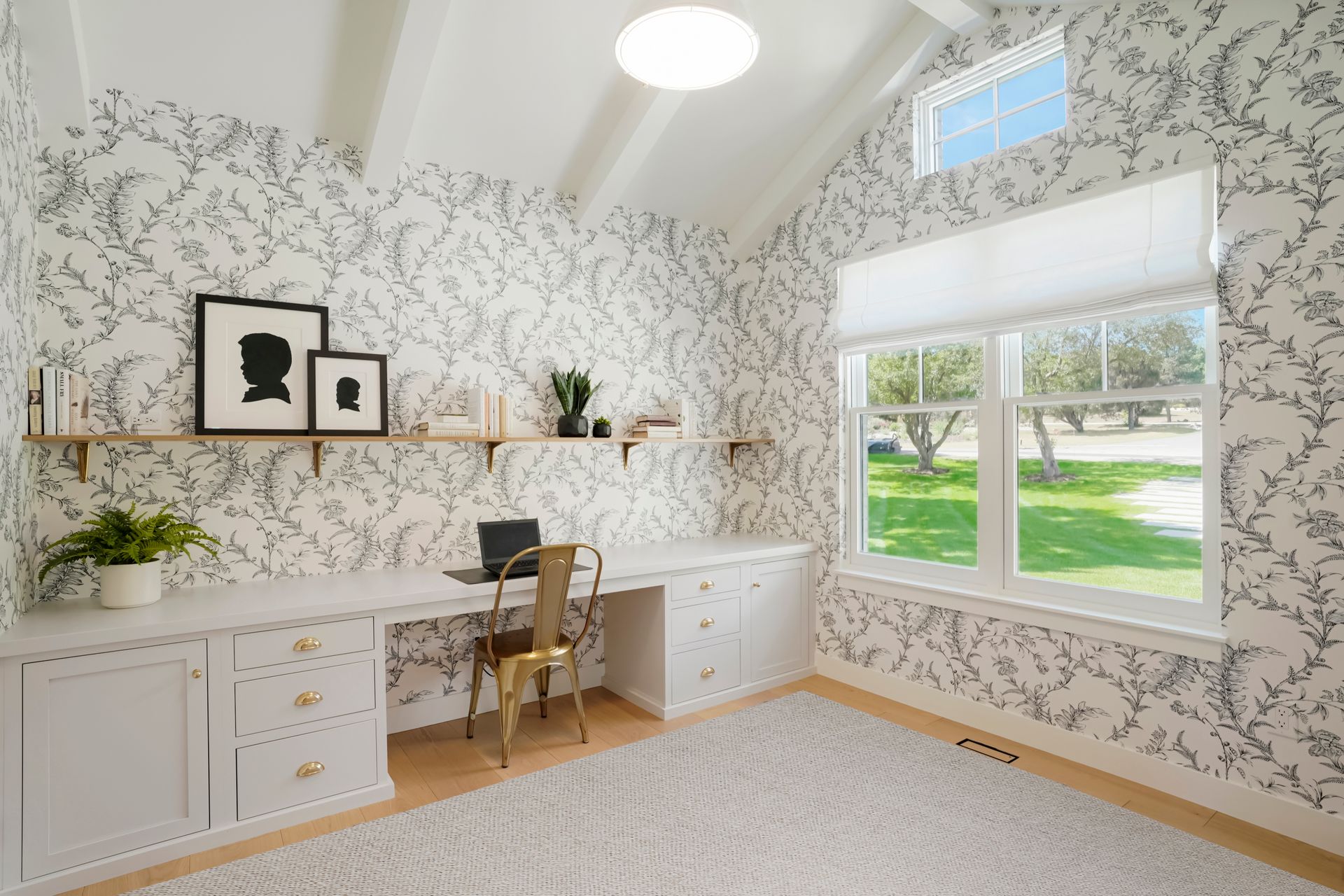 A home office with a desk , chair , shelves and windows.