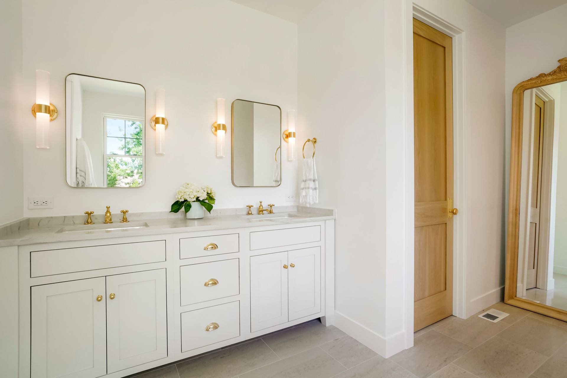 A bathroom with two sinks , a mirror and a door.