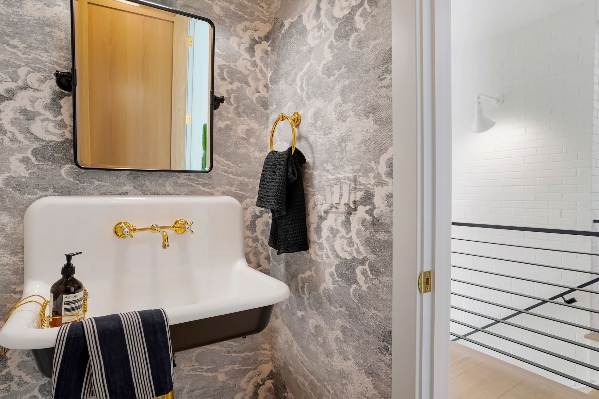 A bathroom with a sink, mirror and towel rack.