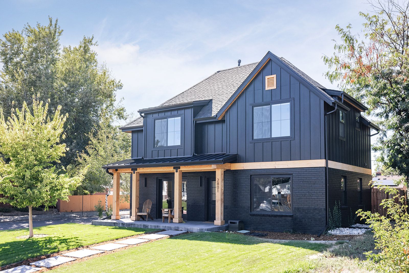 A black house with a lot of windows is sitting on top of a lush green lawn.