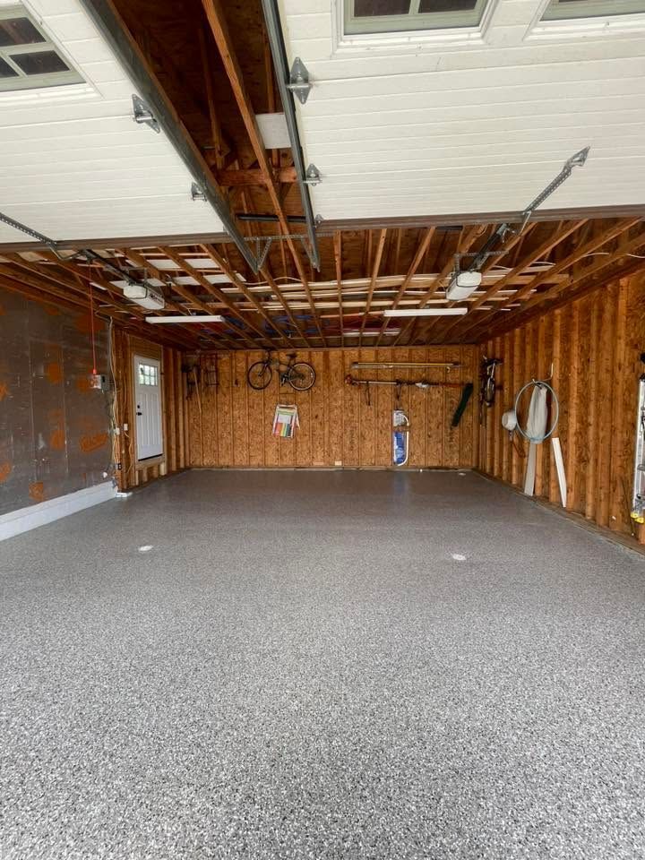 Empty unfinished garage with exposed beams, wood walls, and gray carpeted floor