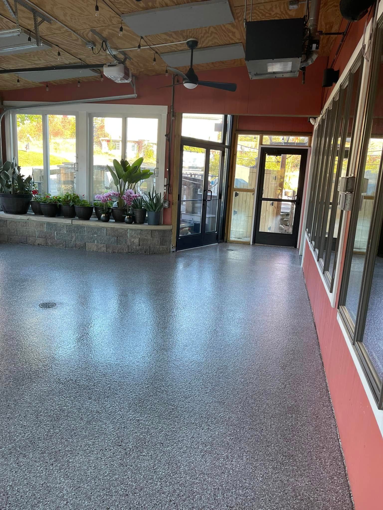 Indoor lobby with speckled terrazzo floor, glass doors, plants, and red walls