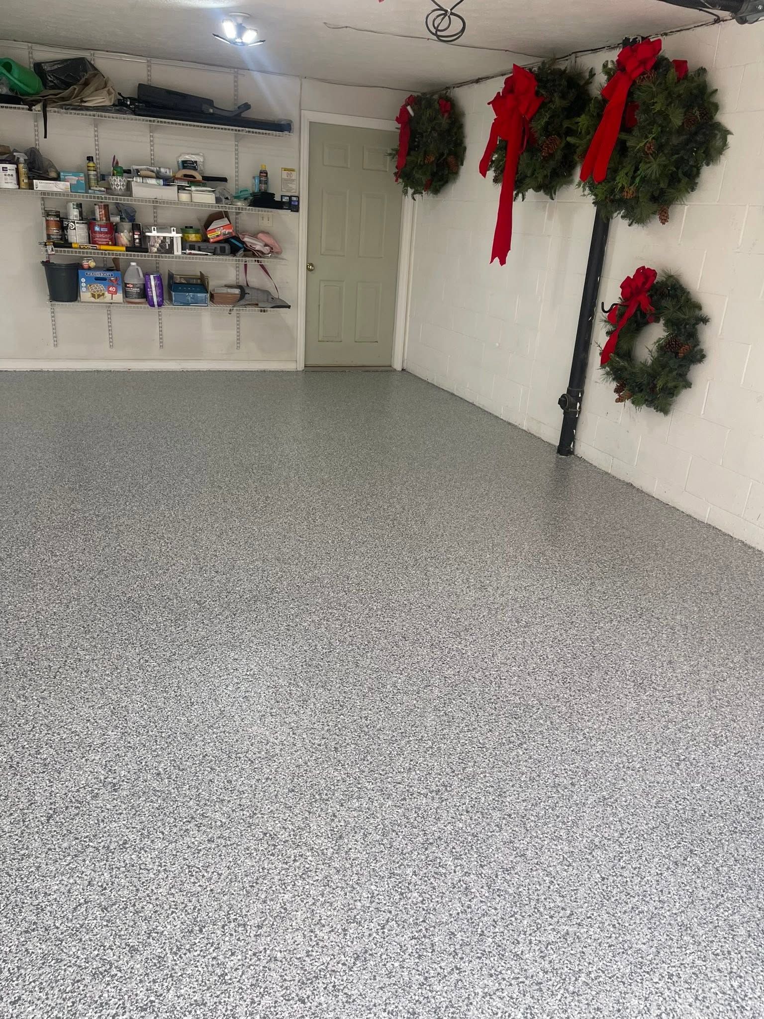 Garage with speckled floor, shelves of supplies, and holiday wreaths on the wall