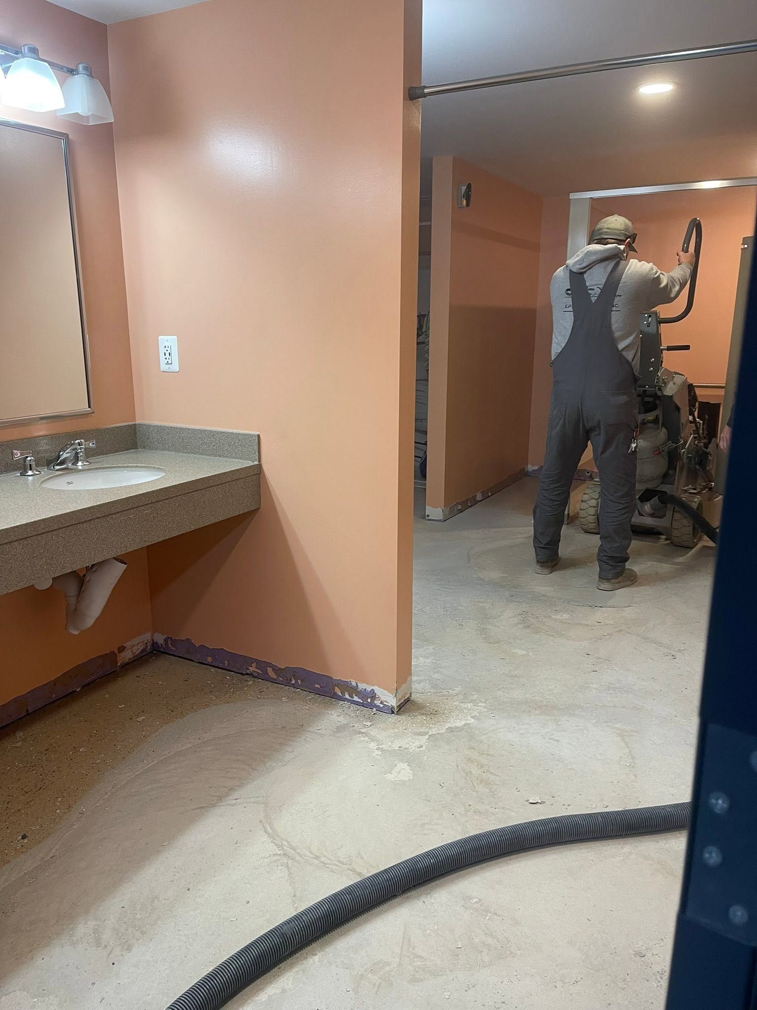 Person in a peach-walled room with sink and counter, standing near a bicycle and vacuum hose.