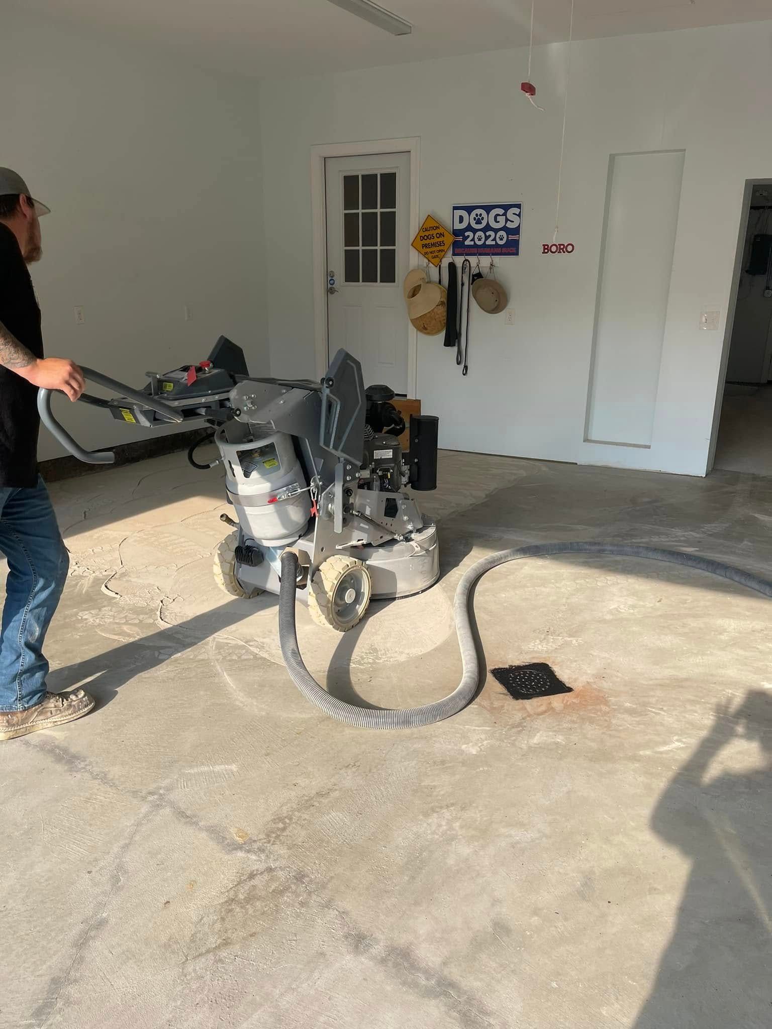 Man using a pressure washer in a garage, cleaning the concrete floor near a wall and doorway