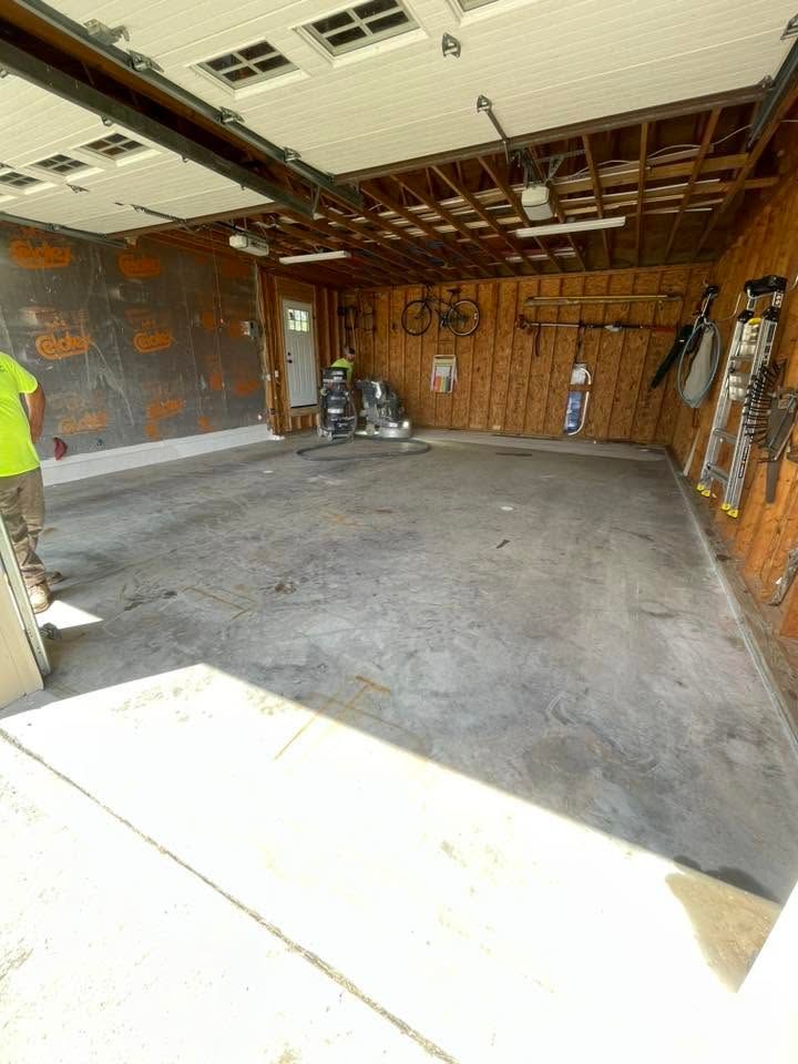 Partially demolished garage interior with exposed framing, debris, and unfinished concrete floor