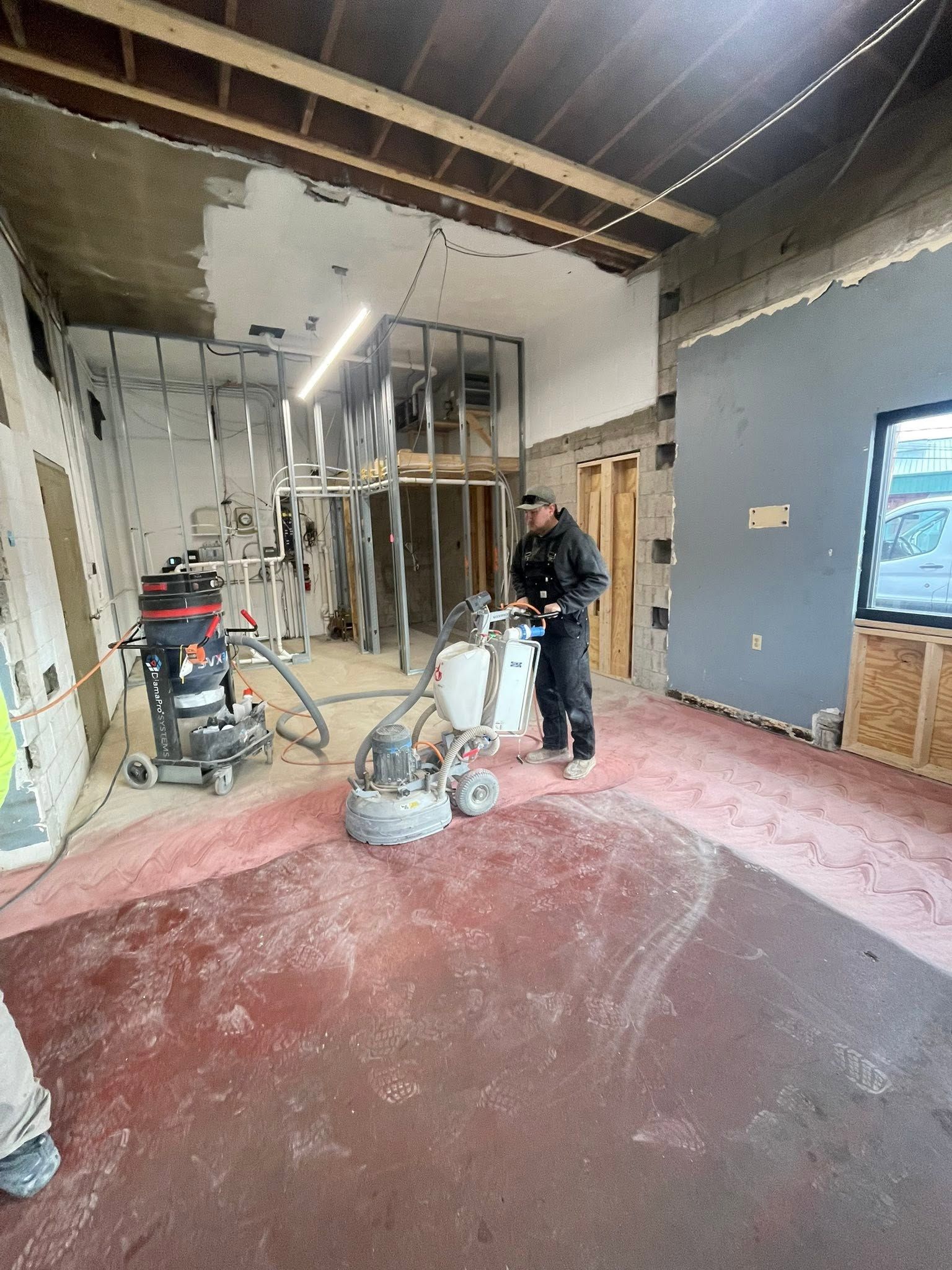 Construction worker in a renovation site with exposed framing, debris, and unfinished walls