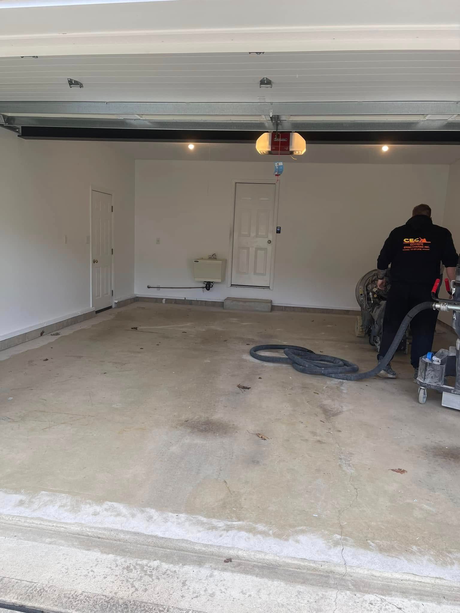 Messy garage interior with a person working near the right wall and tools scattered on the floor.