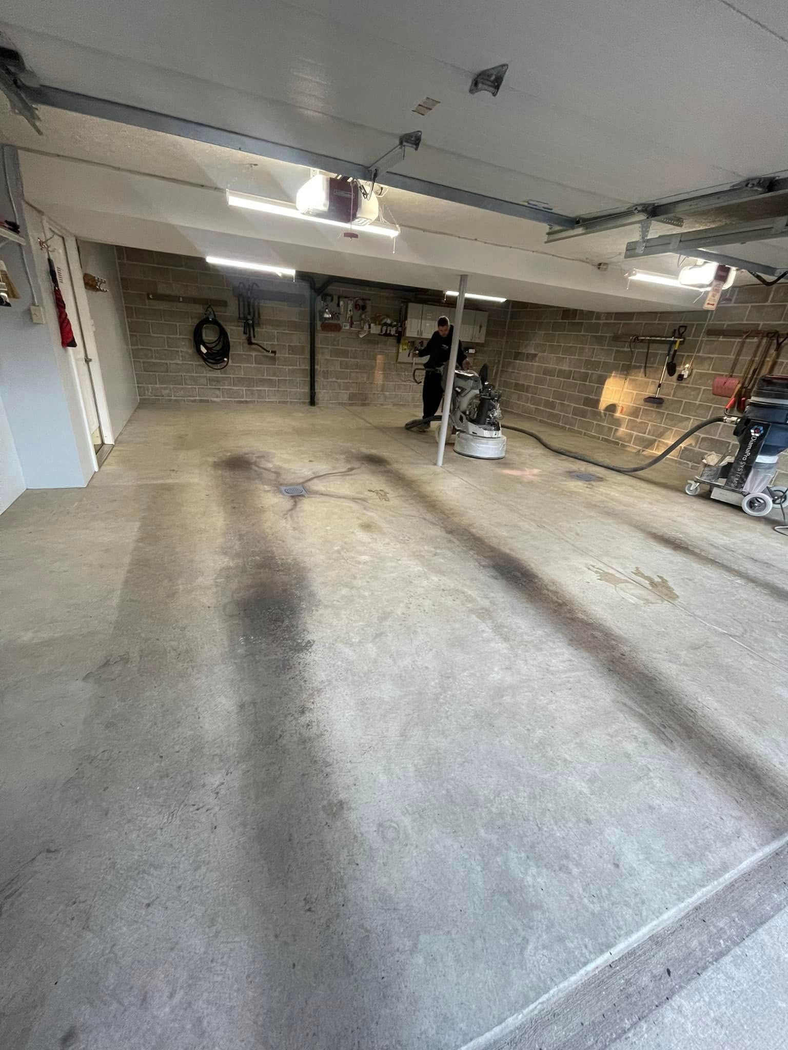 Underground parking garage with concrete floors, low ceiling, parked scooters, and overhead lights.