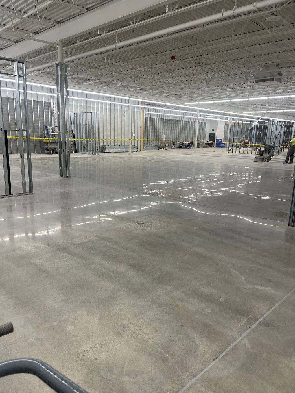 Empty warehouse with polished concrete floor, metal framing, and bright overhead lights