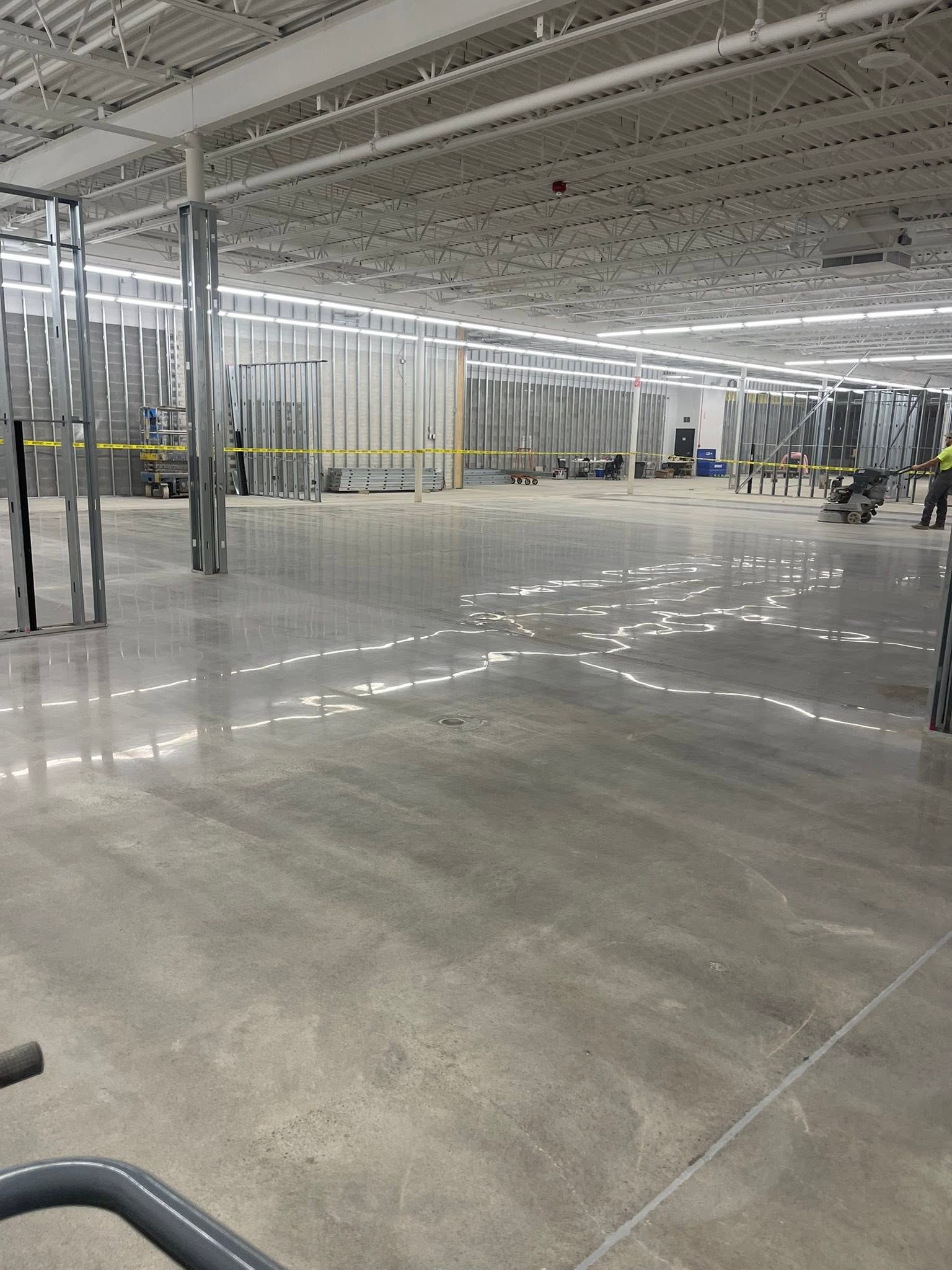 Empty warehouse with polished concrete floor, metal framing, and bright overhead lights