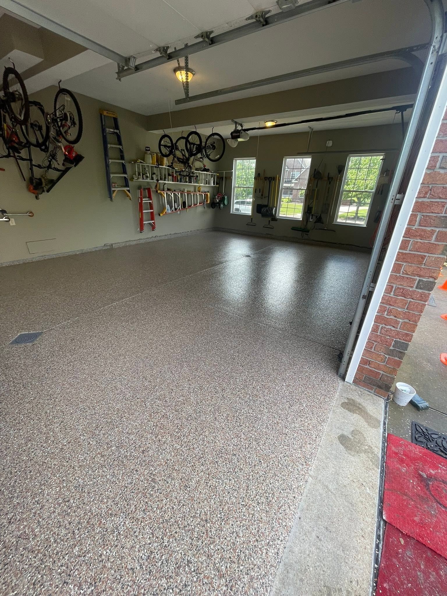 Empty garage with speckled epoxy floor, hanging bikes, and daylight through open doors