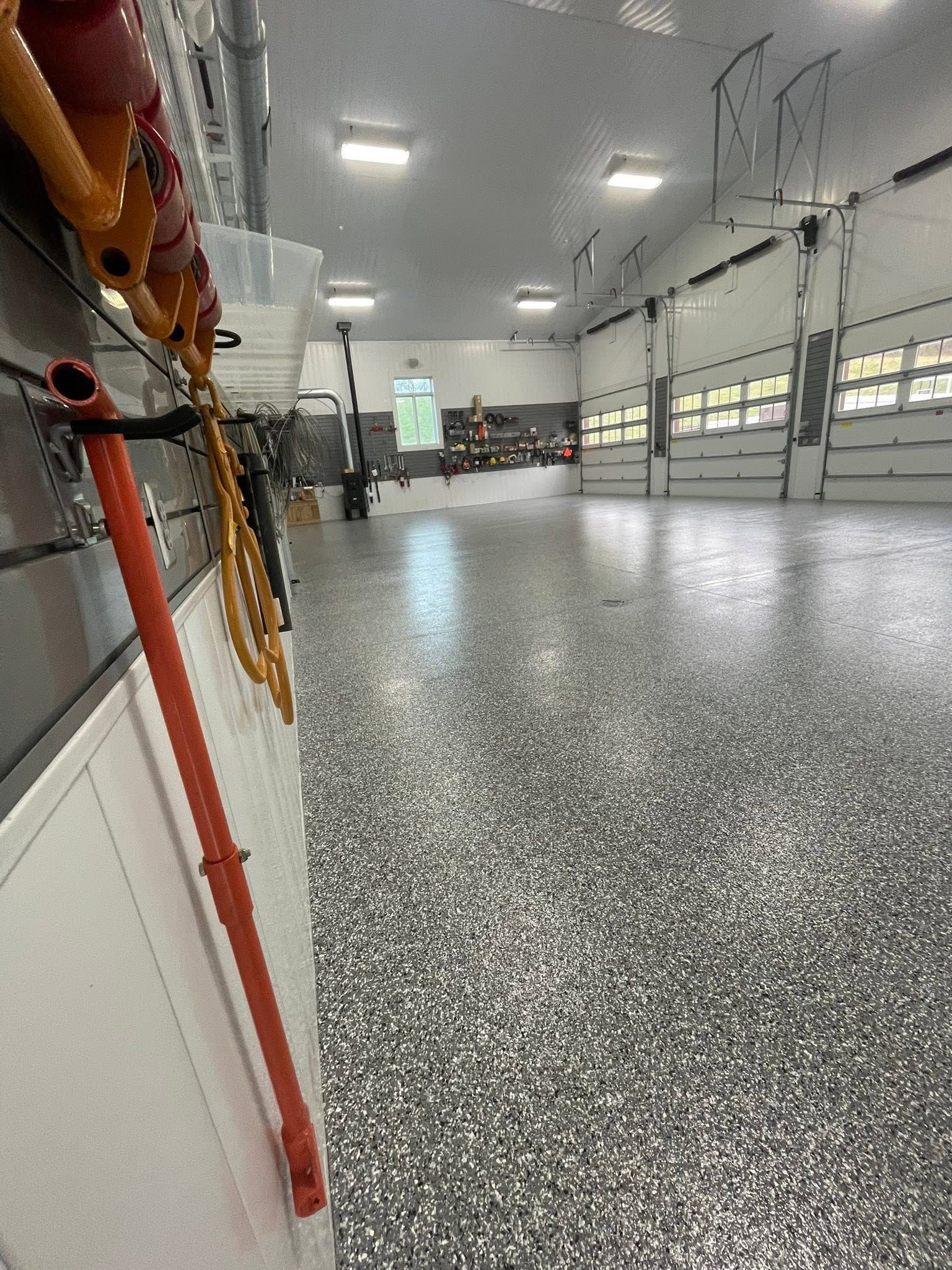 Spacious empty garage with speckled floor, white walls, and bright overhead lights