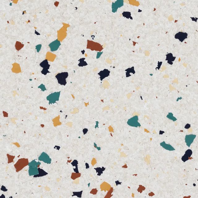 Speckled terrazzo surface with scattered teal, navy, orange, and rust chips on a light background