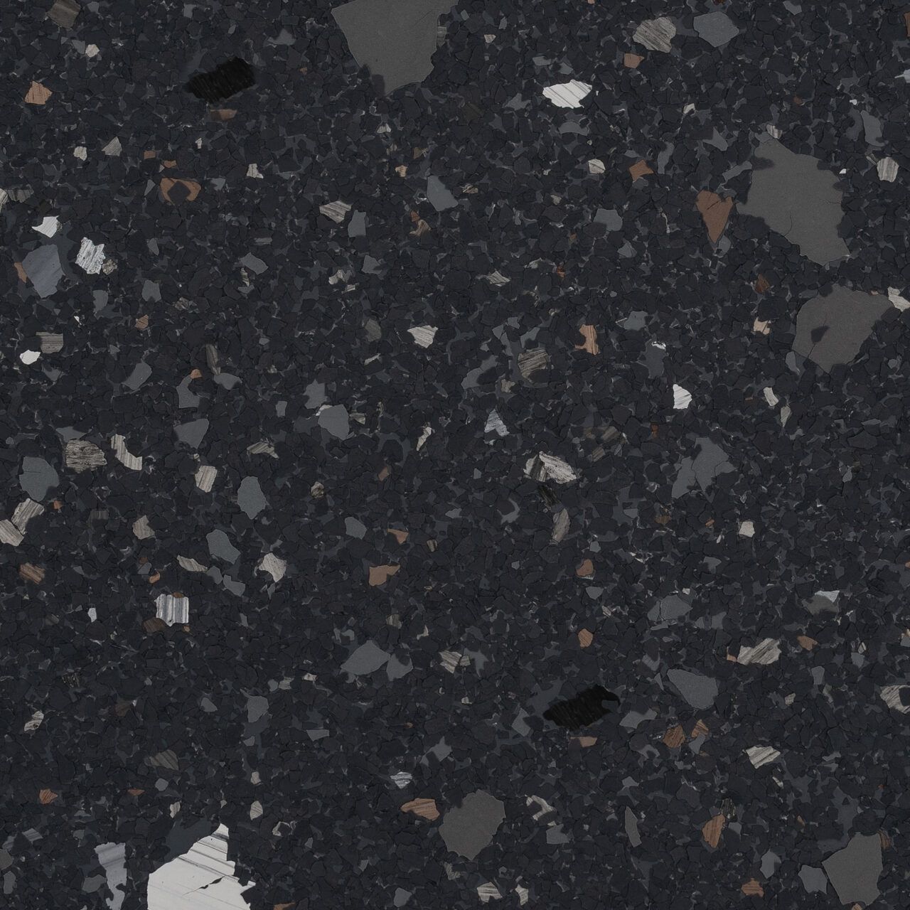 Dark speckled terrazzo or granite surface with scattered gray, white, and brown chips