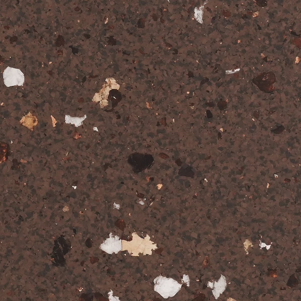 Close-up of dark brown speckled stone or concrete surface with scattered white and tan flecks
