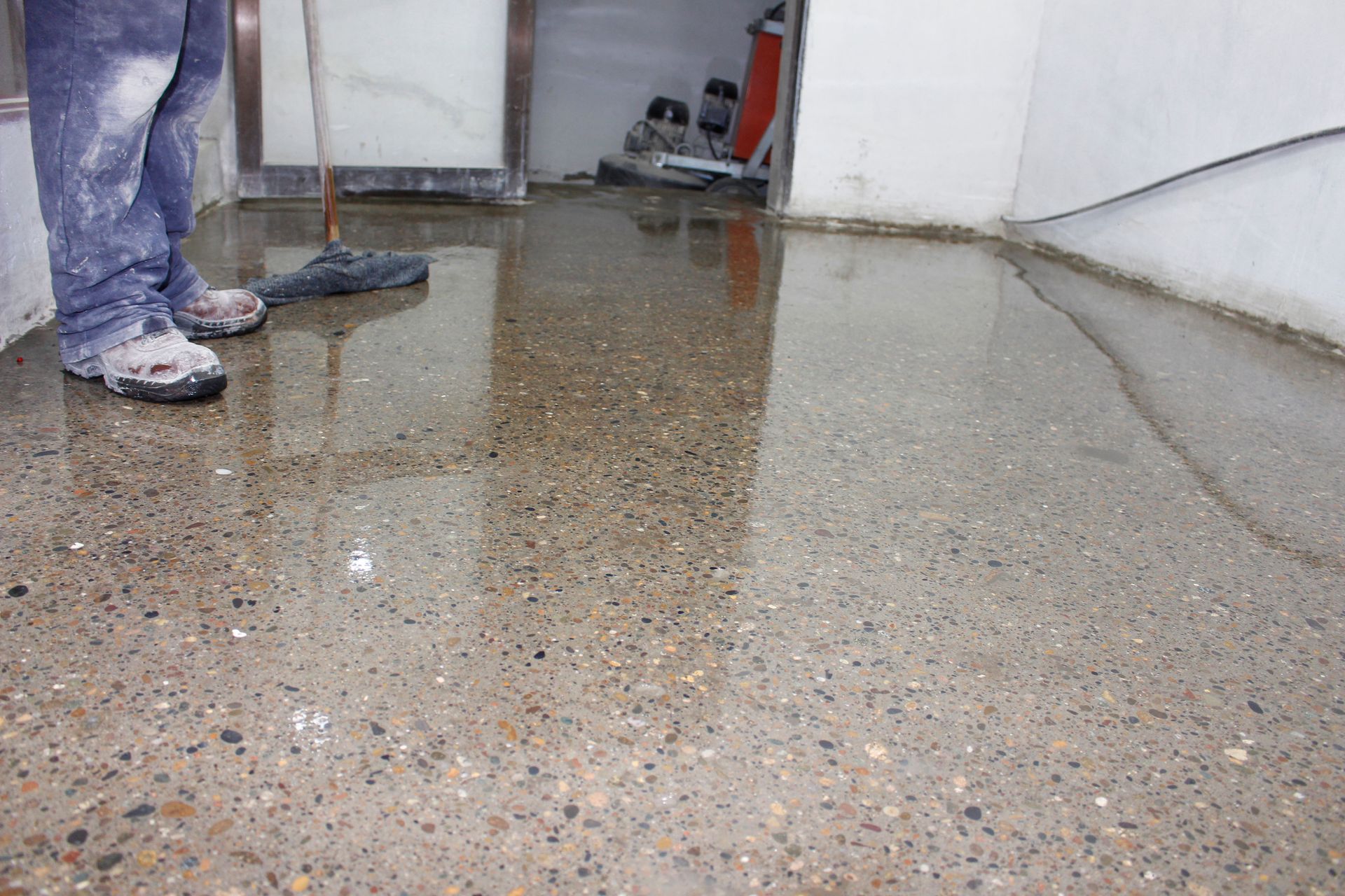 Workers’ boots on a wet, speckled floor in a room under renovation