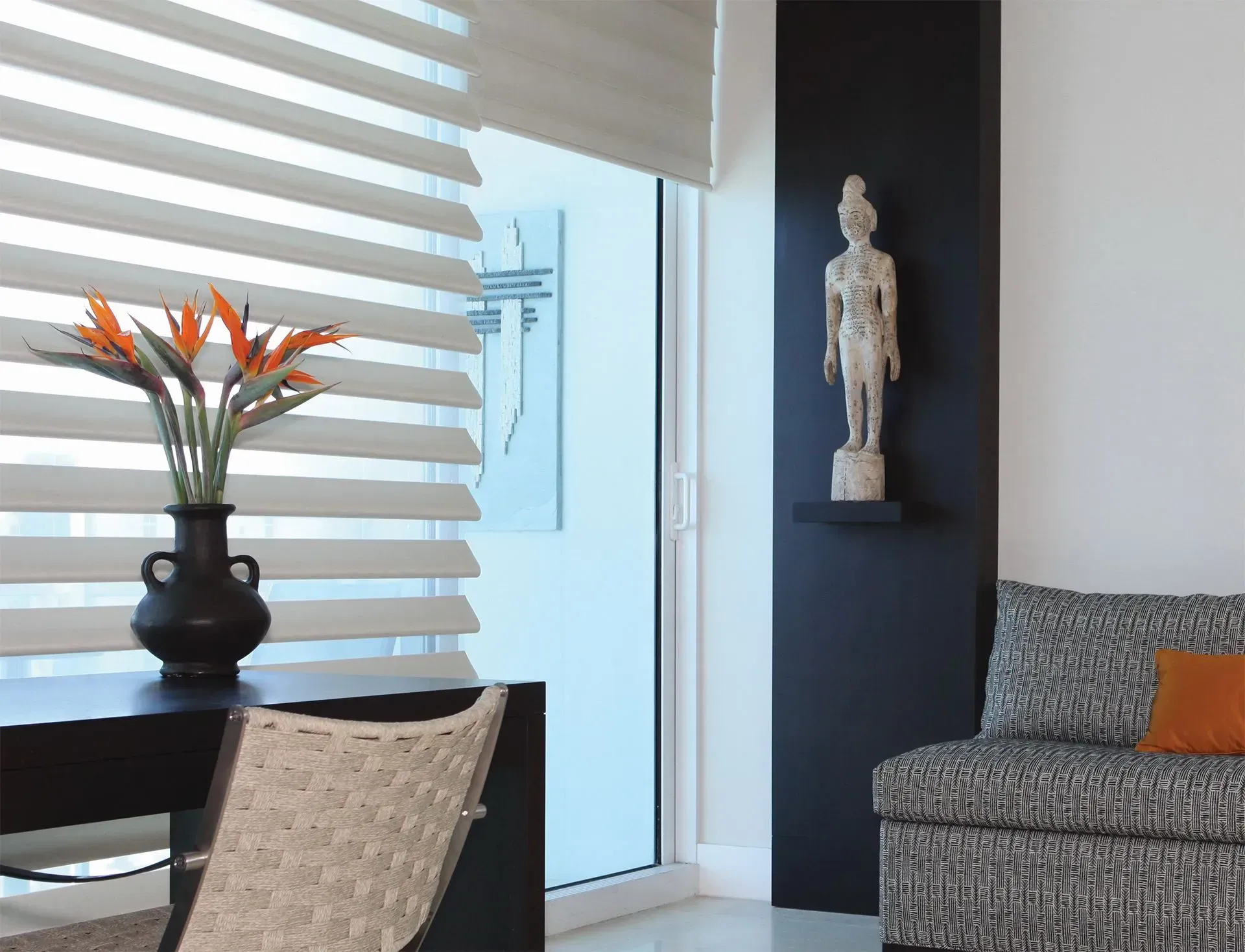 Interior with zebra blinds, flowers, sculpture on shelf, and patterned couch.