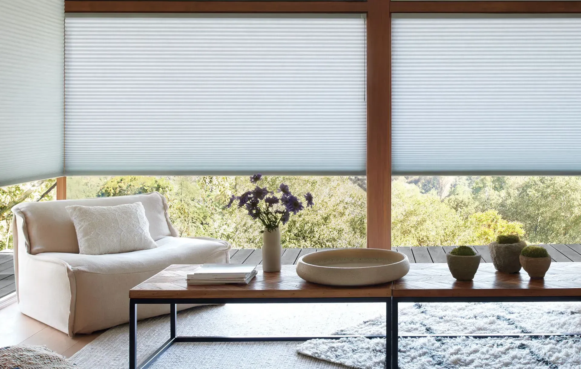 Living room with white honeycomb shades, a light beige chair, and wooden coffee table.
