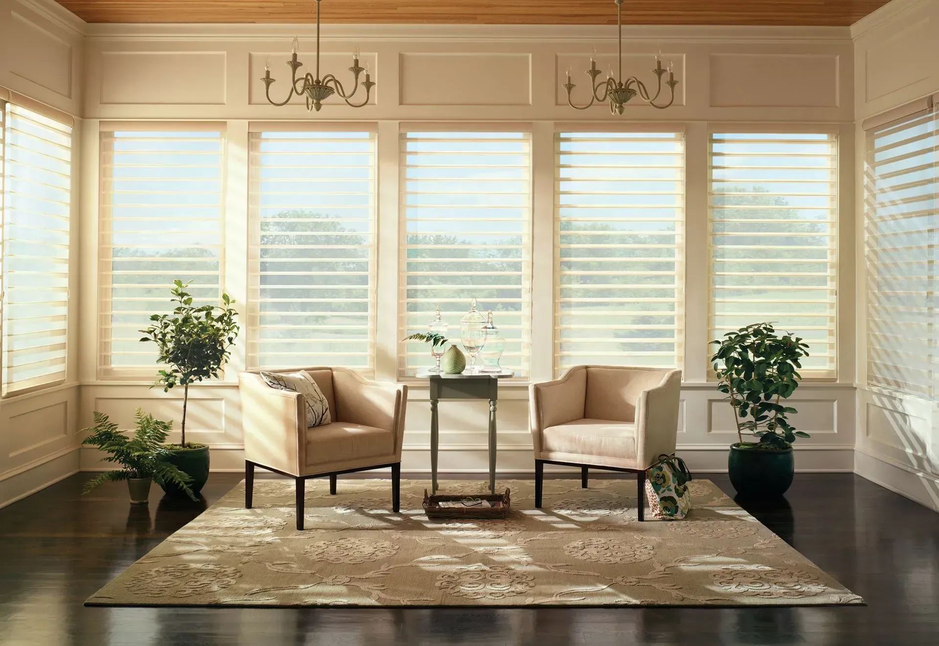 Sunroom with sheer window blinds, armchairs, and plants.