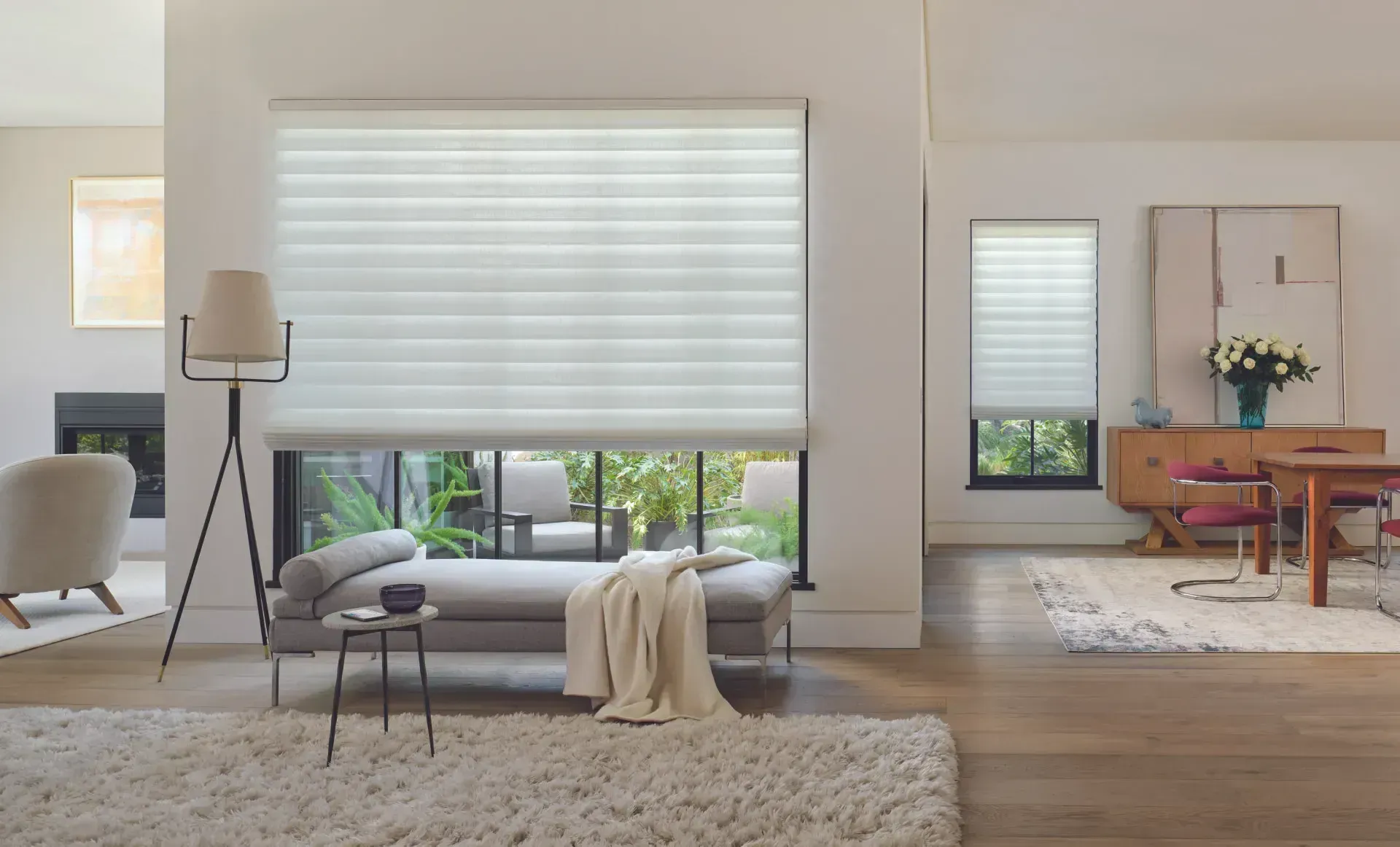 Living room with large windows, sheer white shades, and modern furniture.