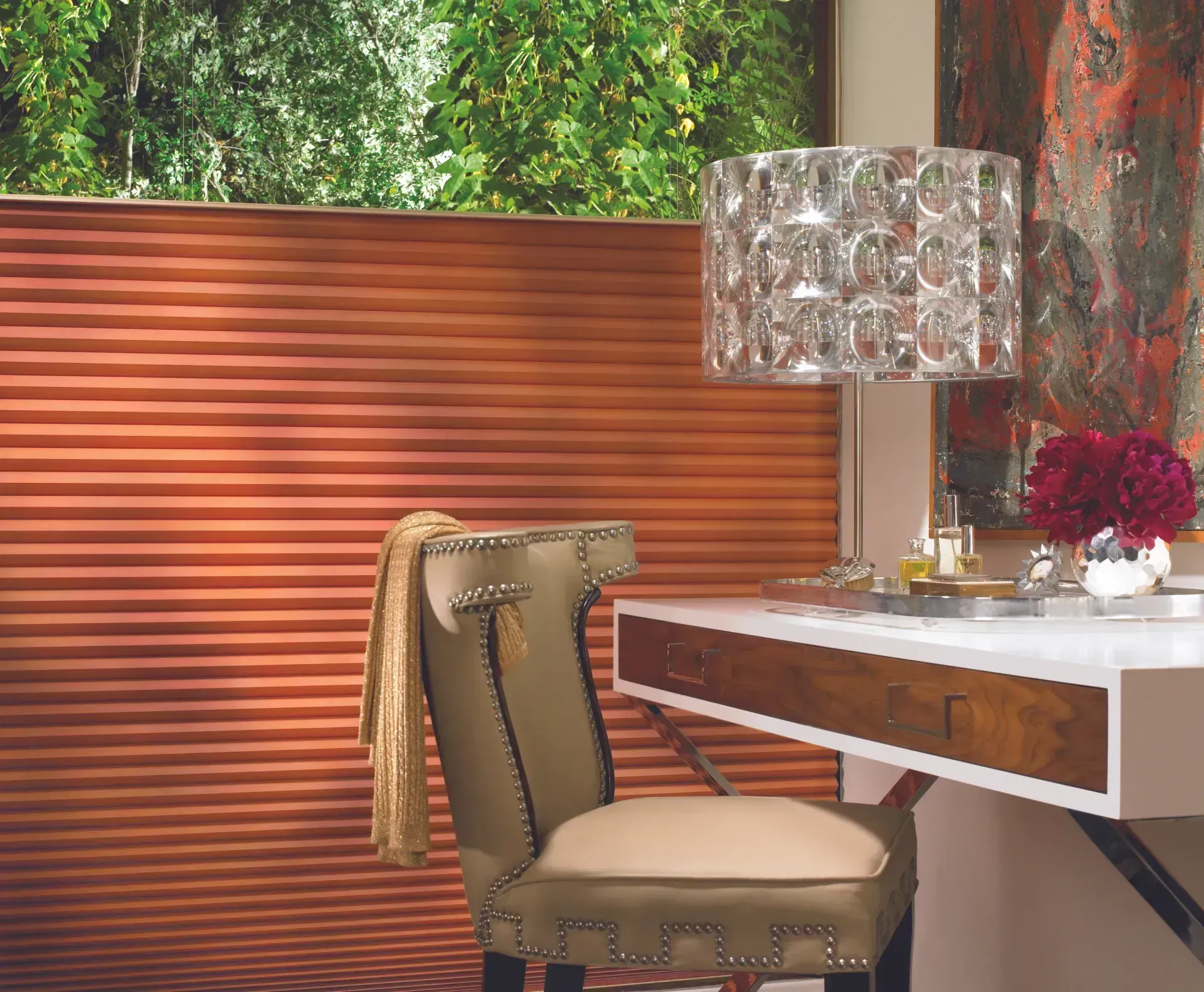 A home office with a desk, chair, and decorative elements; orange pleated window blinds in the background.