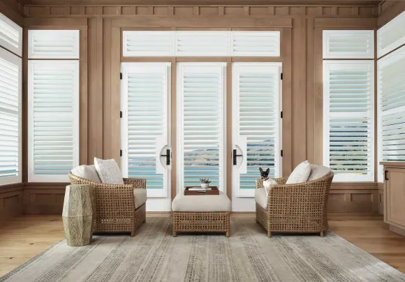 Living room with shutters, wicker chairs, and ocean view. Dog sits in a chair.