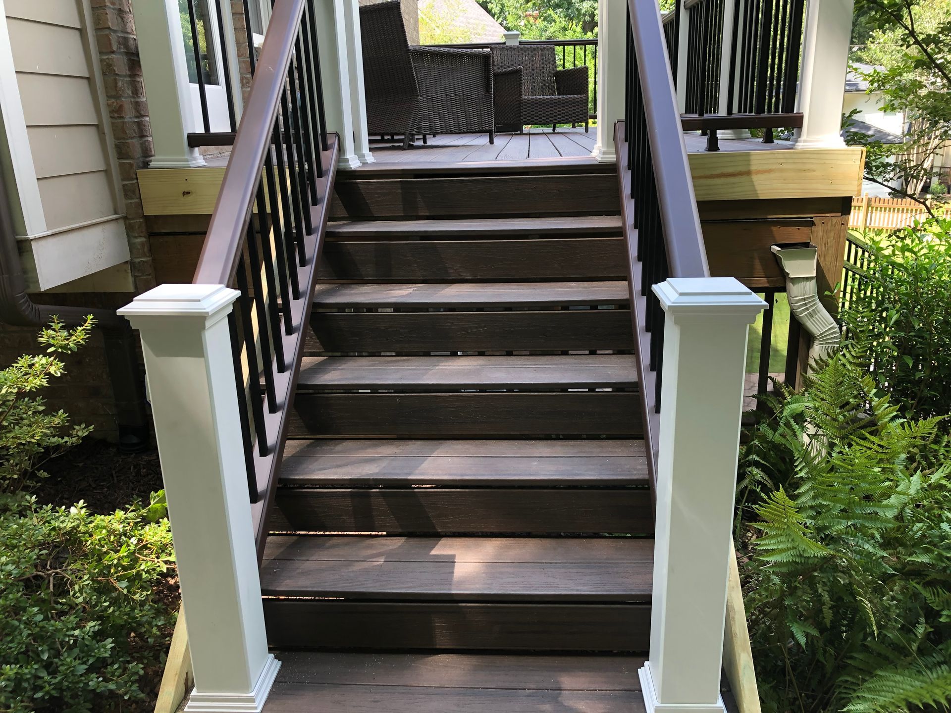 Front steps with dark wooden stairs and white railings leading to a porch.