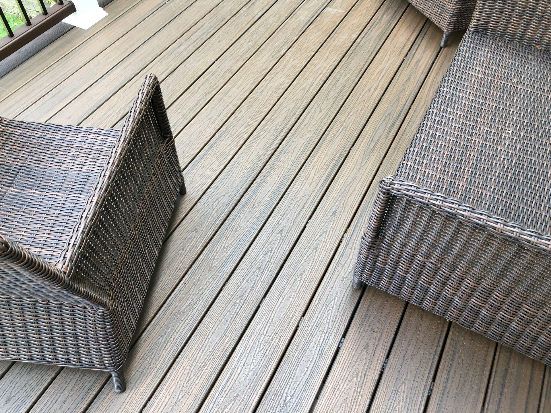 Two wicker patio chairs facing each other on a wooden deck.