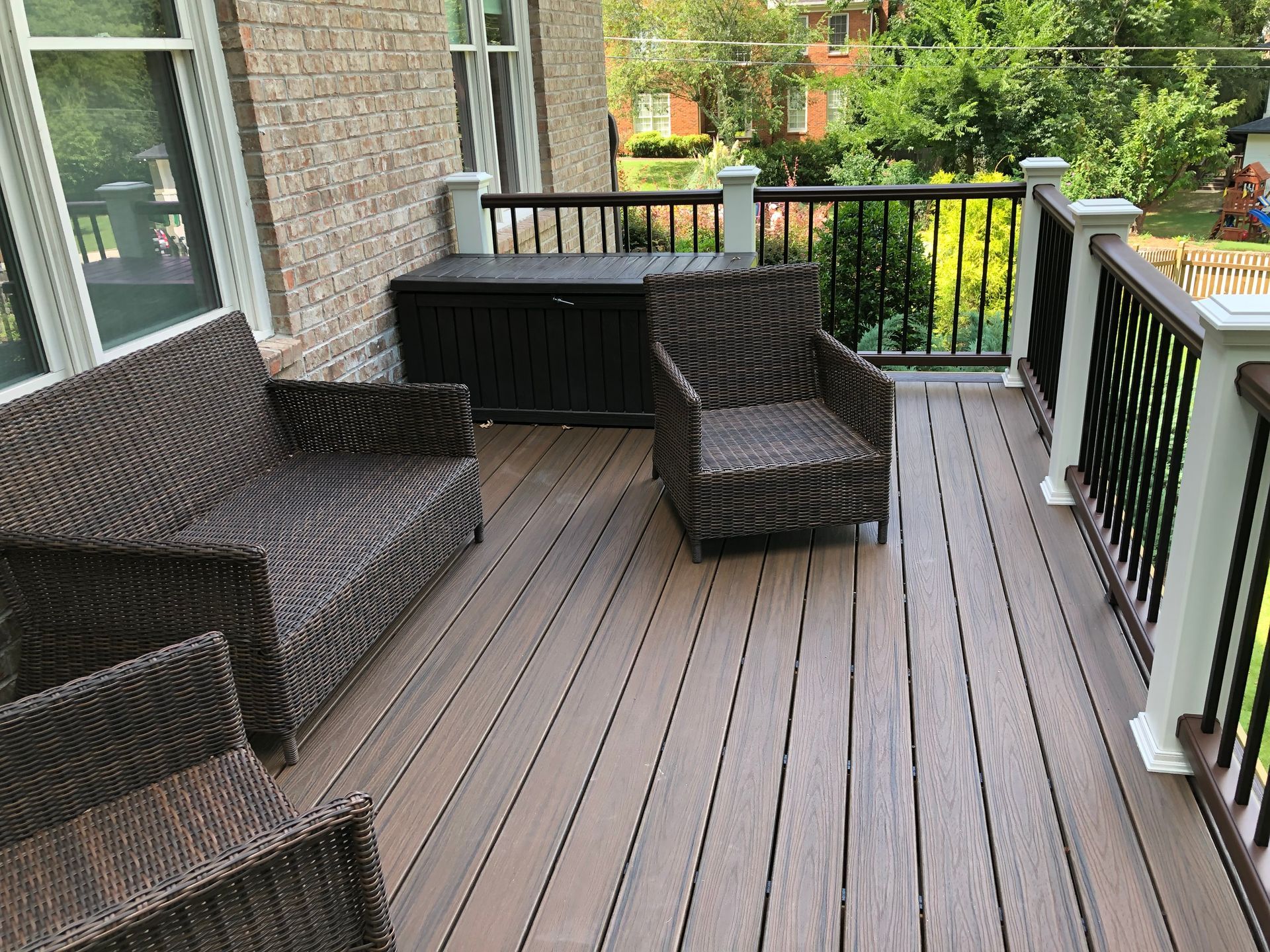 Balcony patio with wicker furniture, wood-look flooring, and a view of trees and neighboring buildings