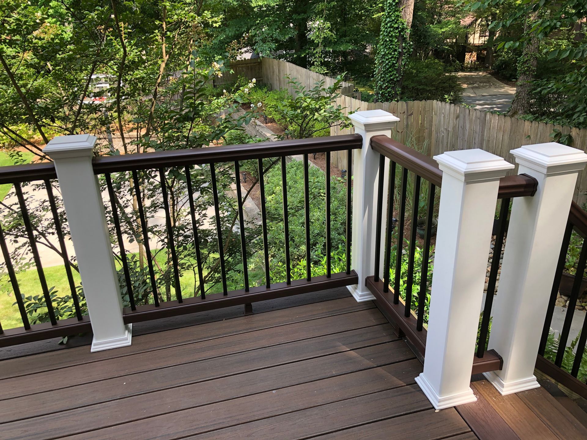 Wooden deck with white railings overlooking a green wooded yard