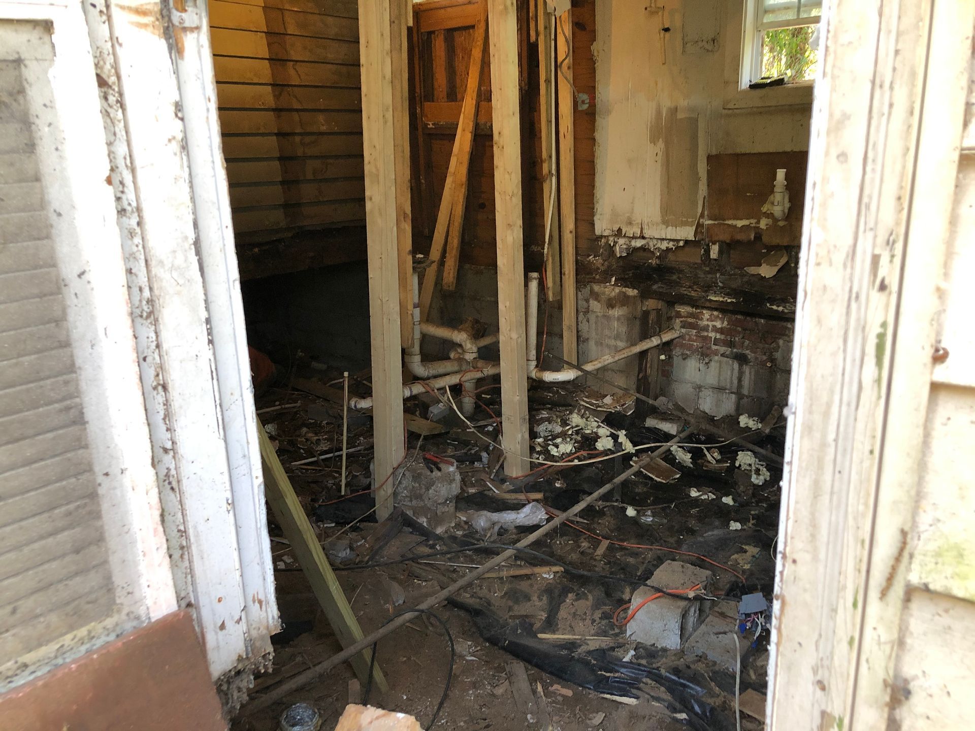 Burned interior room with charred debris, exposed studs, and damaged walls and floor.