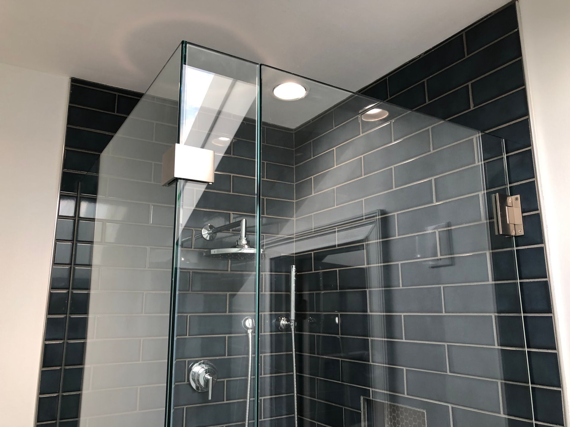 Modern bathroom shower with black subway tiles and a glass enclosure