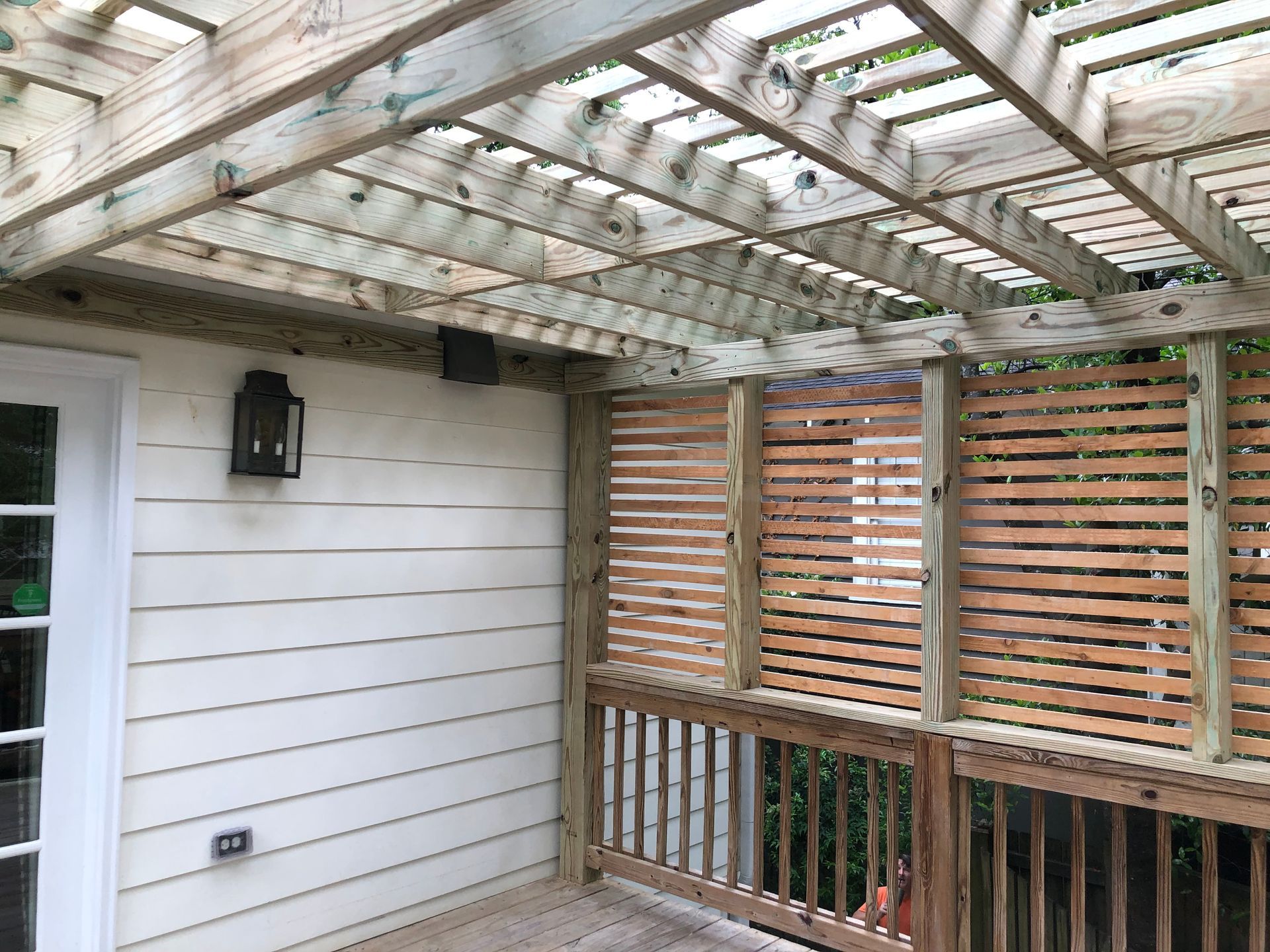 Covered deck with white siding, wooden slat railing, and a translucent roof overhead